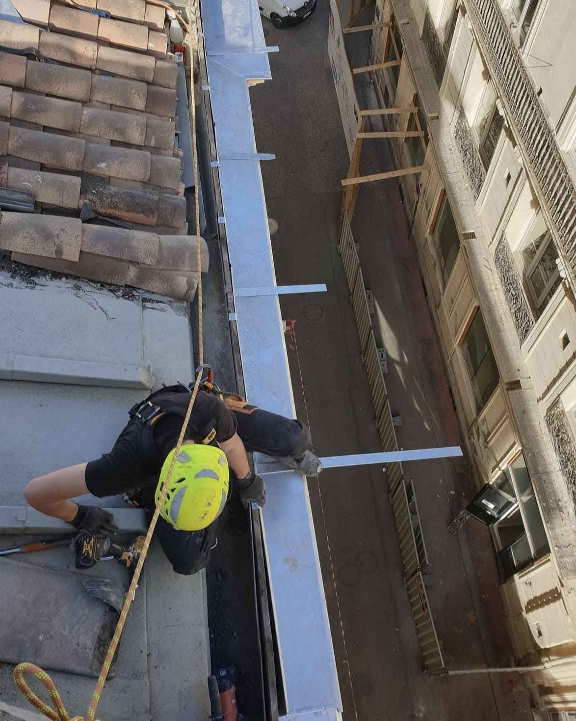 Zingueur en intervention acrobatique pour la mise en place d’un entablement de protection